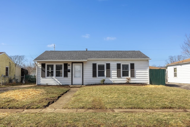 view of front of home with a shingled roof, fence, and a front lawn