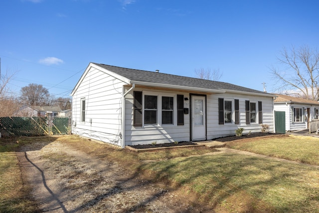 view of front of property with driveway, a front lawn, roof with shingles, and fence