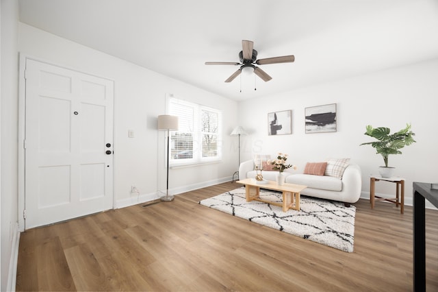 living area with ceiling fan, baseboards, and wood finished floors