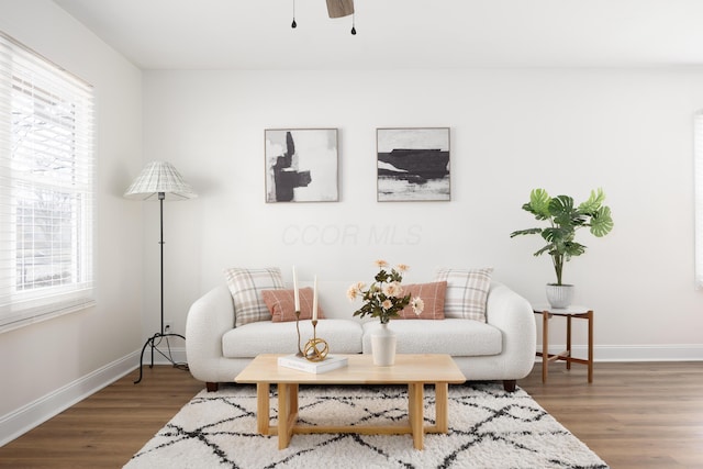 living area featuring ceiling fan, dark wood-type flooring, and baseboards