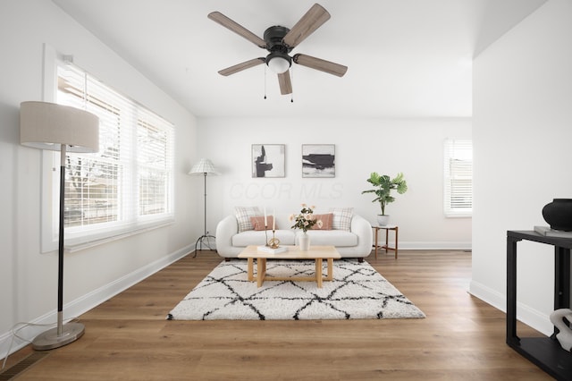 living room featuring ceiling fan, baseboards, and dark wood-style flooring