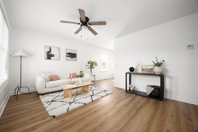 living area featuring a ceiling fan, baseboards, and wood finished floors