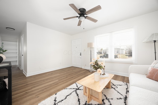 living room featuring a ceiling fan, baseboards, and wood finished floors