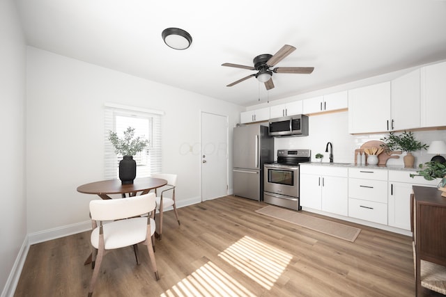 kitchen featuring stainless steel appliances, light wood-type flooring, white cabinets, and a sink