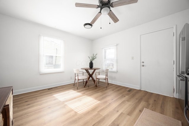 unfurnished office featuring light wood-style flooring, a ceiling fan, visible vents, and baseboards