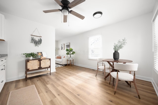 living area with light wood-style flooring, baseboards, and ceiling fan