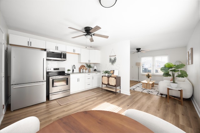 kitchen with a sink, stainless steel appliances, light countertops, and white cabinets