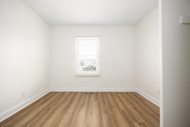 unfurnished room with light wood-style floors, visible vents, and baseboards