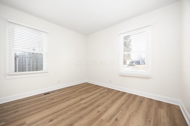 unfurnished room with wood finished floors, visible vents, and baseboards