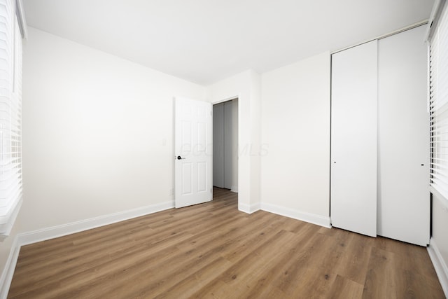 unfurnished bedroom featuring a closet, wood finished floors, and baseboards