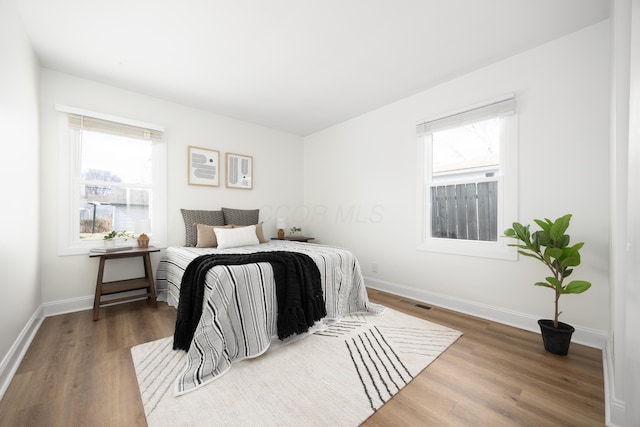 bedroom with dark wood-style flooring, multiple windows, and baseboards