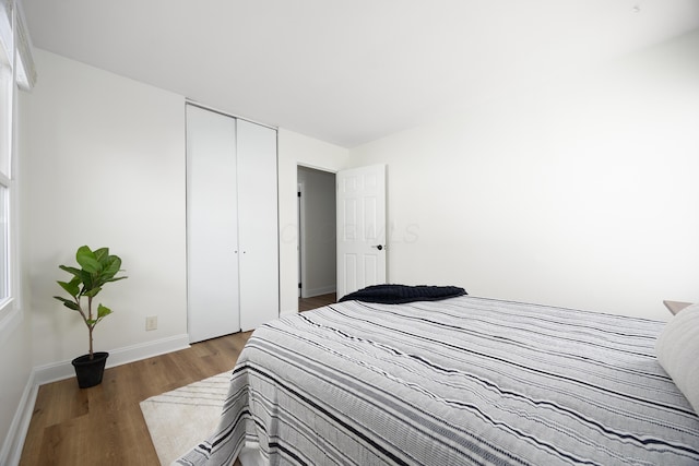 bedroom with a closet, baseboards, and wood finished floors