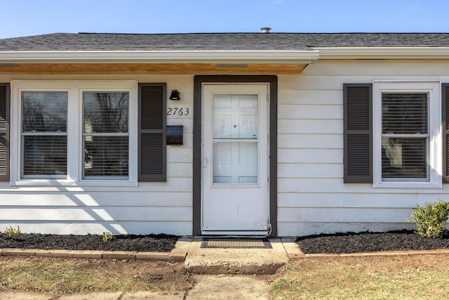 entrance to property featuring a shingled roof