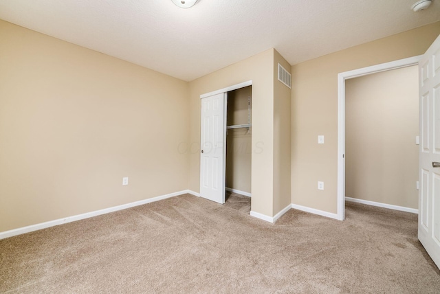 unfurnished bedroom featuring light carpet, baseboards, visible vents, and a closet