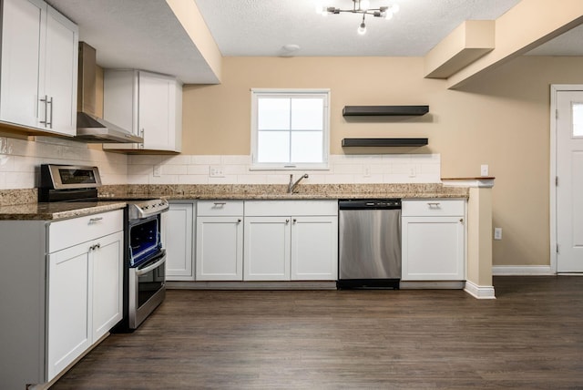 kitchen featuring stainless steel appliances, wall chimney exhaust hood, and white cabinetry