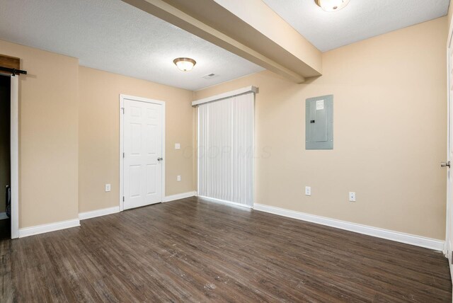 unfurnished bedroom with a barn door, electric panel, baseboards, dark wood-style floors, and a textured ceiling