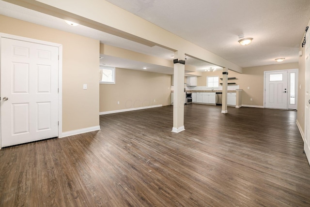 basement featuring plenty of natural light, dark wood finished floors, and baseboards