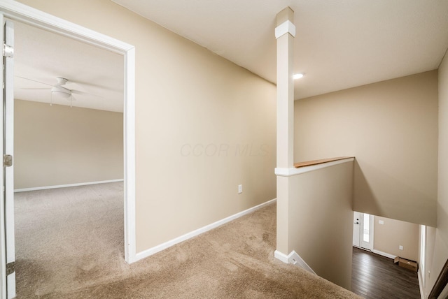 corridor featuring carpet flooring, an upstairs landing, and baseboards