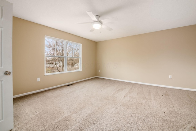 carpeted empty room with ceiling fan, visible vents, and baseboards