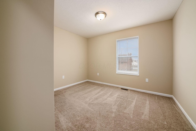 empty room with a textured ceiling, carpet, visible vents, and baseboards