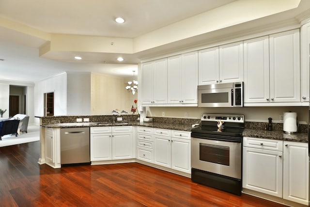 kitchen with a peninsula, white cabinets, open floor plan, appliances with stainless steel finishes, and dark wood finished floors