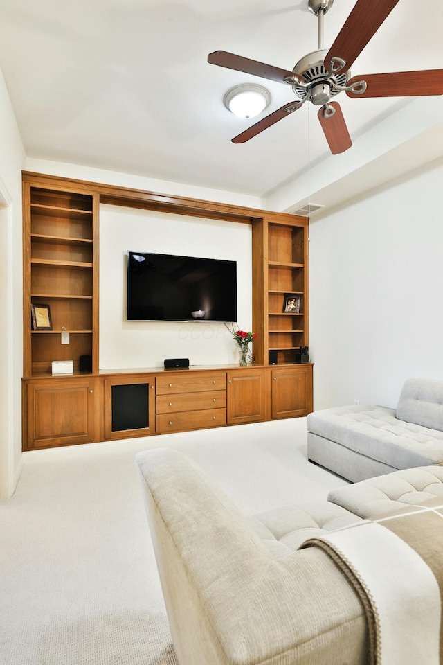 carpeted living room with ceiling fan and built in shelves