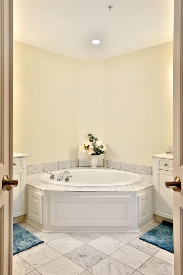 full bath with marble finish floor, vanity, and a bath