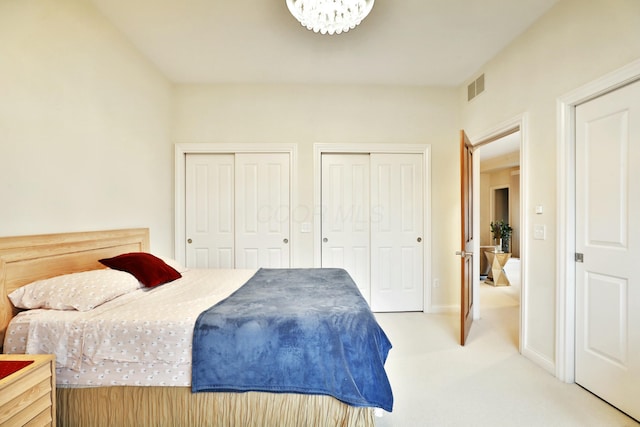 carpeted bedroom featuring visible vents, baseboards, and two closets