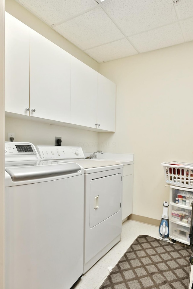 clothes washing area with light floors, independent washer and dryer, cabinet space, and baseboards