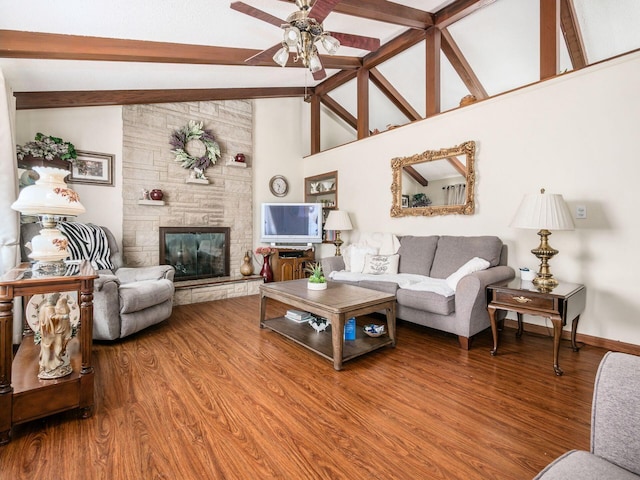 living room with baseboards, ceiling fan, wood finished floors, a stone fireplace, and beam ceiling