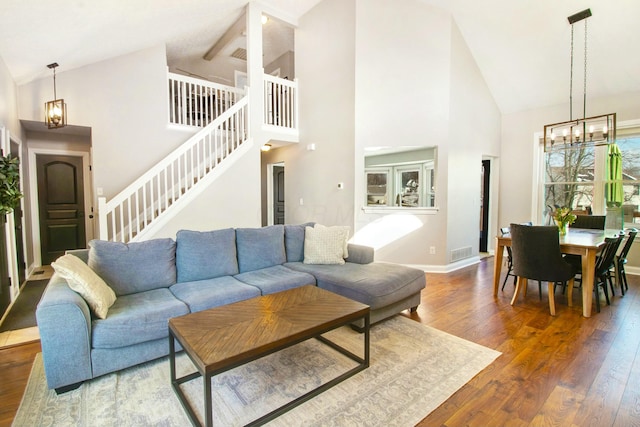 living area featuring visible vents, baseboards, wood-type flooring, stairs, and a chandelier