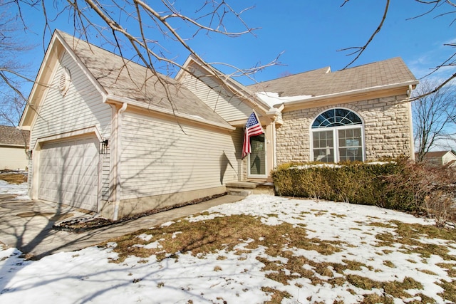 view of front of property with stone siding, a shingled roof, an attached garage, and driveway