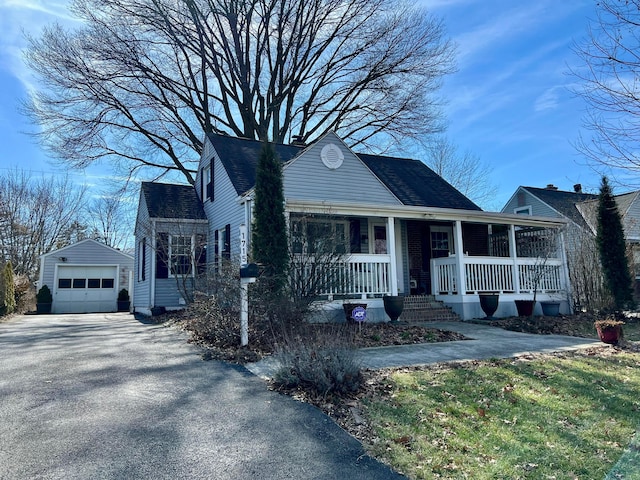 view of front facade with a garage, a shingled roof, aphalt driveway, an outbuilding, and covered porch