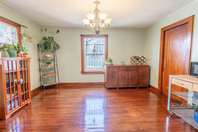 living area with an inviting chandelier, baseboards, and wood finished floors