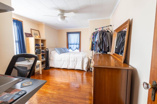 bedroom with a ceiling fan, multiple windows, crown molding, and wood finished floors