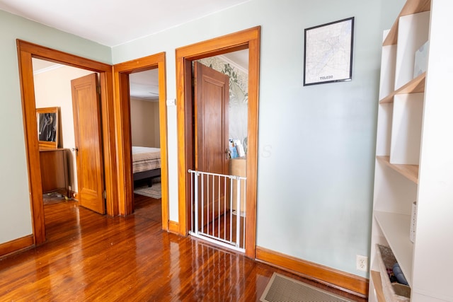 corridor with visible vents, baseboards, and wood finished floors