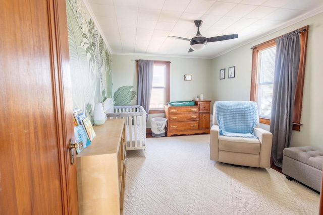 sitting room featuring a ceiling fan, light carpet, and crown molding