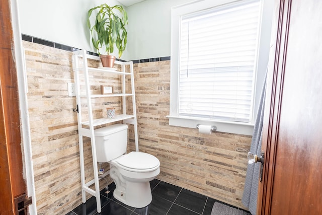 bathroom with tile patterned flooring, a wainscoted wall, and toilet