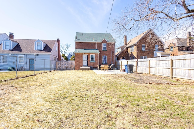 back of house featuring entry steps, a fenced backyard, brick siding, a yard, and a patio area