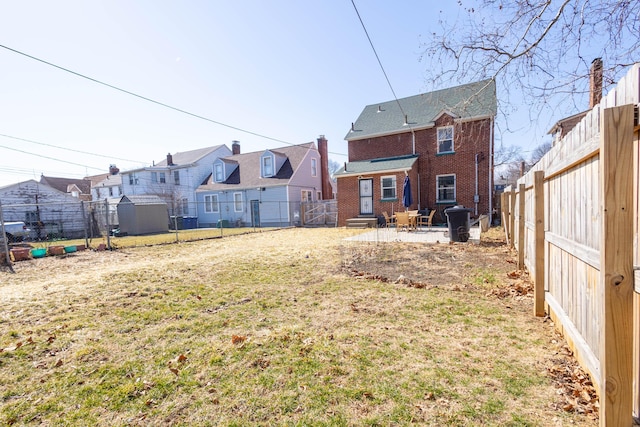 back of house with entry steps, brick siding, a patio area, and a fenced backyard