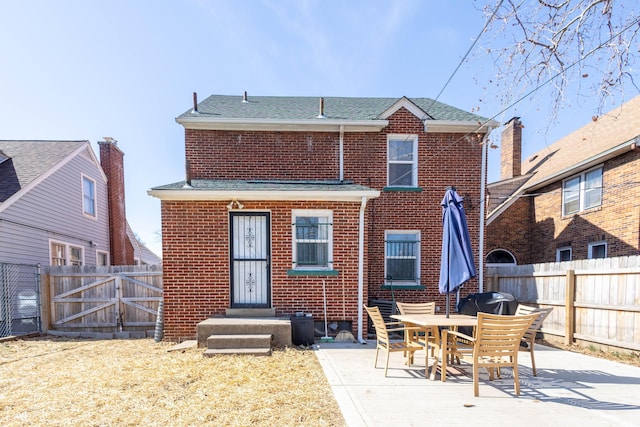 rear view of property with brick siding, a patio, a shingled roof, a gate, and fence