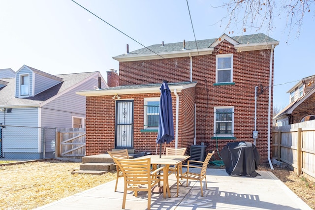 rear view of house featuring entry steps, fence, a patio, and brick siding