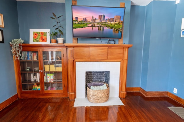 details with visible vents, a fireplace, baseboards, and wood finished floors