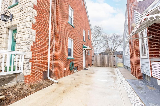 view of side of property featuring a gate, brick siding, and fence