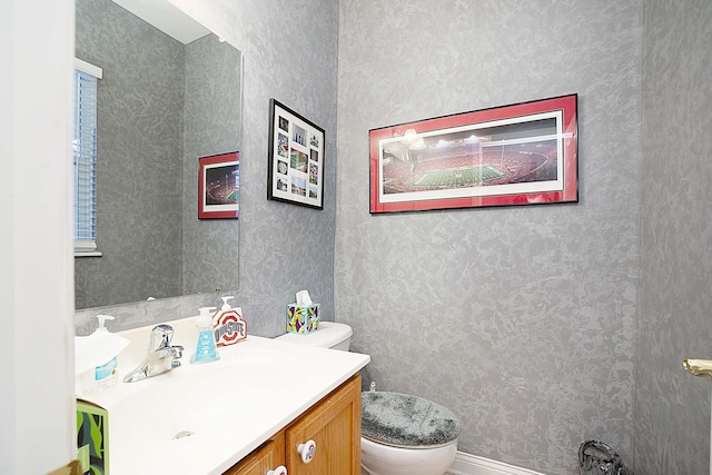 bathroom with vanity, toilet, and wallpapered walls