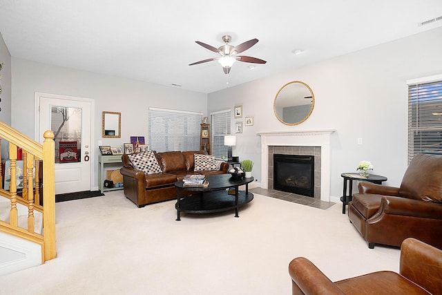 living area with a ceiling fan, carpet, visible vents, and a tiled fireplace