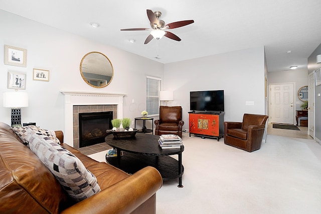 living area with ceiling fan, a tile fireplace, and carpet flooring