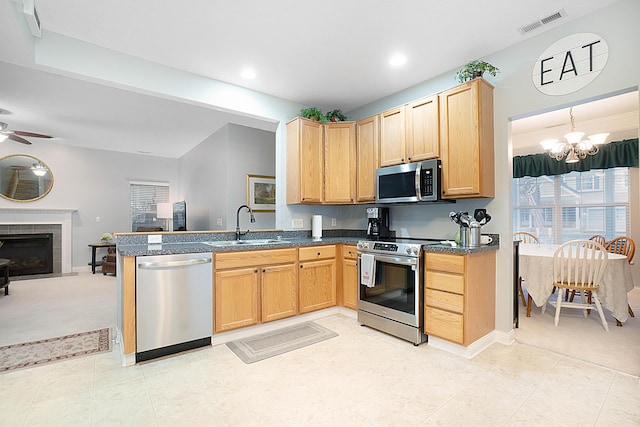 kitchen with stainless steel appliances, a sink, visible vents, open floor plan, and dark countertops