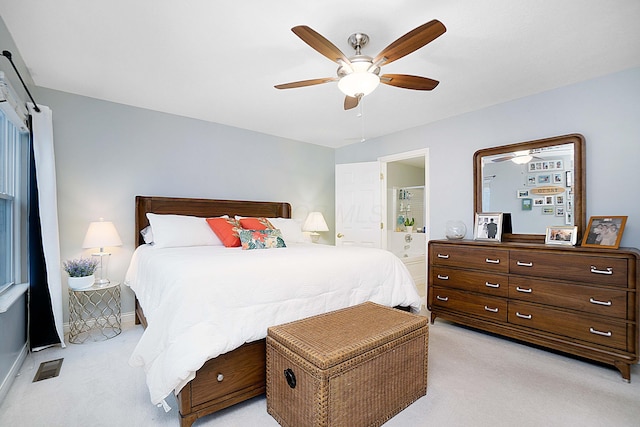 bedroom featuring light colored carpet, a ceiling fan, baseboards, visible vents, and ensuite bath