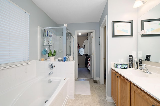 bathroom featuring vanity, a bath, tile patterned floors, a stall shower, and a walk in closet